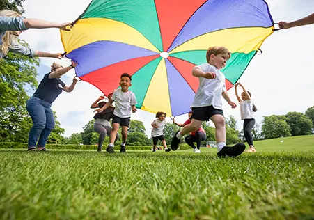 Preschool aged children playing outside with parachute